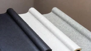 Rolled samples of various types of rubber roofing membranes, including black (EPDM), white (TPO/PVC), and a granular-coated white or gray material.